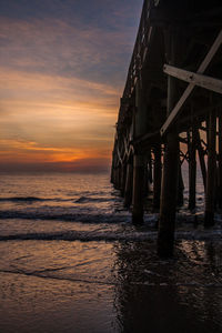 Pier over sea against sky during sunset