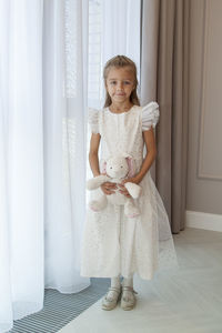 Portrait of smiling girl standing against curtain at home