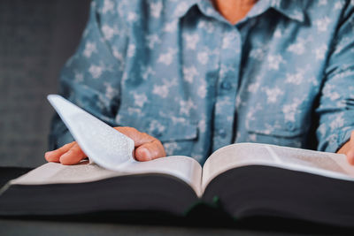 Midsection of woman reading book at home