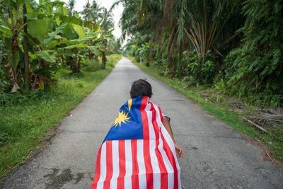 Rear view of boy with malaysian flag on road 