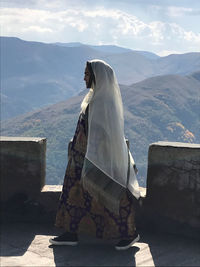 Side view of woman walking on fort terrace with mountains in background