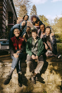 Portrait of happy friends from lgbtq community sitting on porch at sunny day