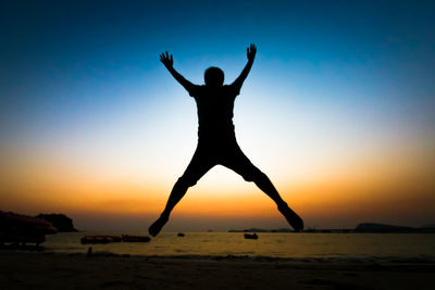 Silhouette man at beach against sky during sunset