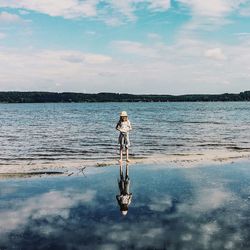 Full length of girl standing on lakeshore against sky