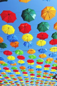 Low angle view of multi colored umbrellas hanging against clear sky