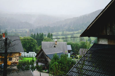 High angle view of houses and trees against raining sky