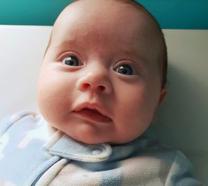 Close-up of cute baby girl lying on bed at home