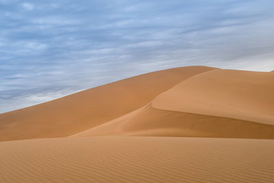 Sand dunes in desert against sky