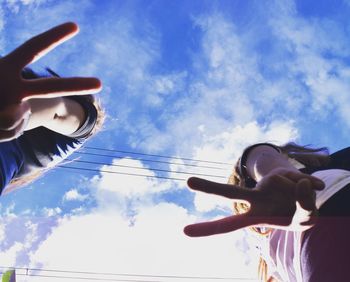 Low angle view of hands against sky