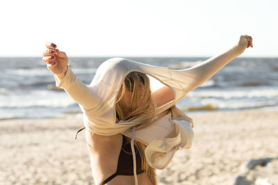 Woman wearing top at beach against clear sky