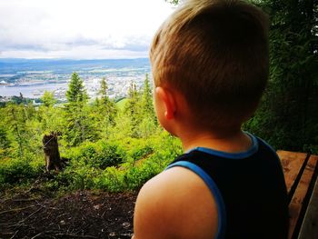 Rear view of boy with horse on landscape against sky