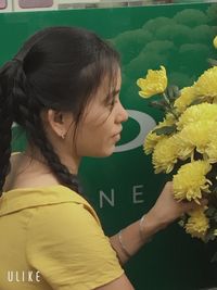 Close-up of woman by yellow flowering plant