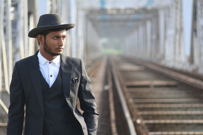 Portrait of young man standing on railroad track