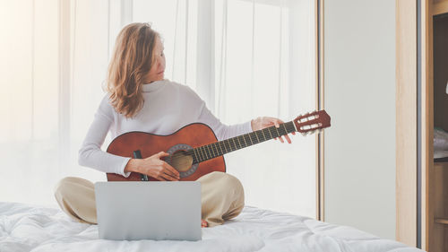 Young woman playing guitar at home