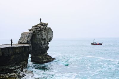 Scenic view of rock formation in sea against clear sky