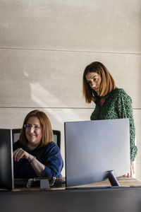 Businesswoman with female colleague discussing over computer