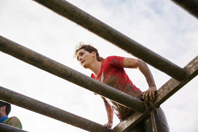 Low angle view of woman climbing structure against sky during race