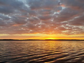 Scenic view of sea against dramatic sky during sunset