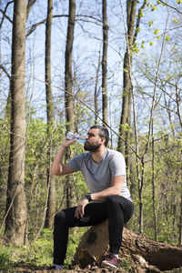 Young man sitting on tree trunk in forest