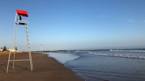 Lifeguard hut on beach against clear blue sky