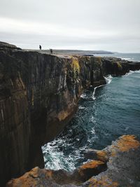 Cliff by sea against sky