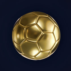 Close-up of golden soccer ball against blue background