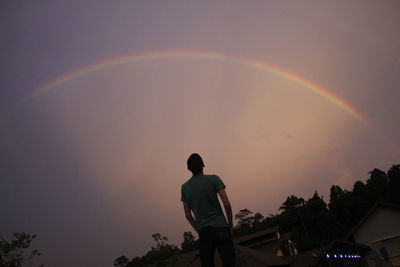 Rear view of man looking at rainbow in sky