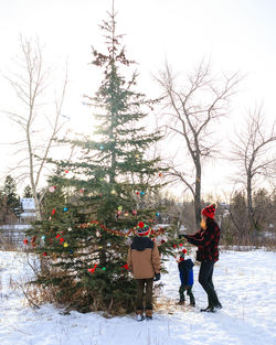 Woman and children decorating a christmas tree in a park