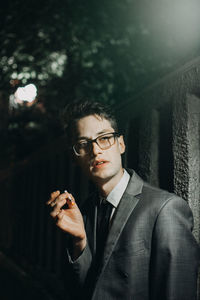 Businessman smoking cigarette by illuminated wall at night