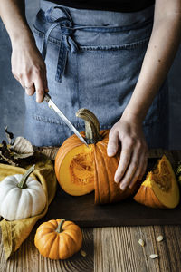 Midsection of woman cutting pumpkins at table