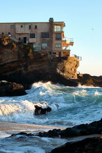 Buildings by sea against clear sky