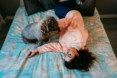 High angle view of woman with dog lying on bed at home