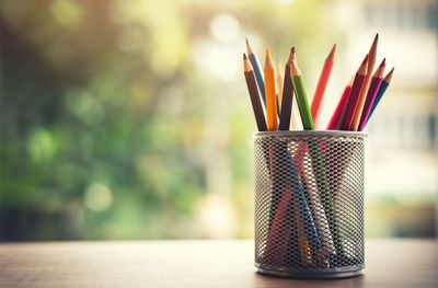 Close-up of multi colored pencils in jar on table