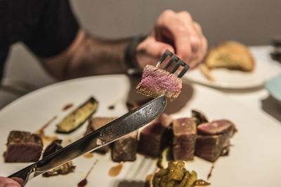 Close-up of hand eating meat on table