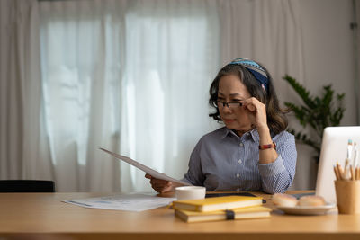 Businesswoman using mobile phone while sitting on table