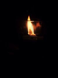 Close-up of lit candle in darkroom