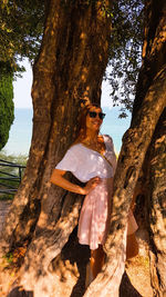 Woman with tree trunk against sky