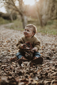 Cute boy looking away while sitting on land