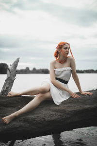 Portrait of young woman sitting on rock at beach