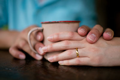 Cropped image of couple holding coffee cup at table