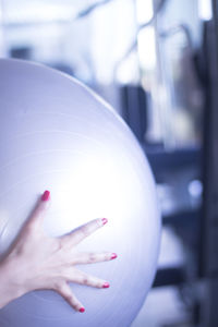 Cropped hand of woman holding fitness ball in gym