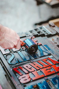 A mans hand rolling paint onto a letterpress machine 