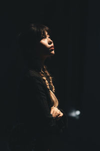 Young woman standing against black background