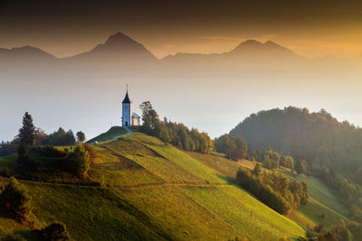 Scenic view of church on landscape against mountain range