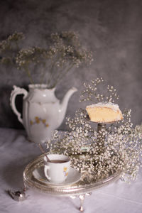 White still life with cheesecake and gypsophila and cup of tea, light and airy