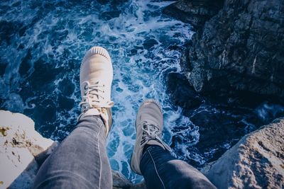 Low section of person sitting on cliff