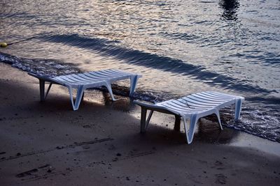 High angle view of empty chairs and table at beach