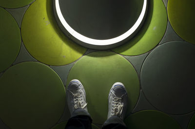 Low section of person standing on green shoes