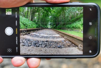 Cropped image of hand on railroad track