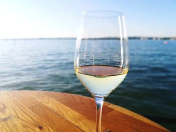 Close-up of wine in front of sea against sky